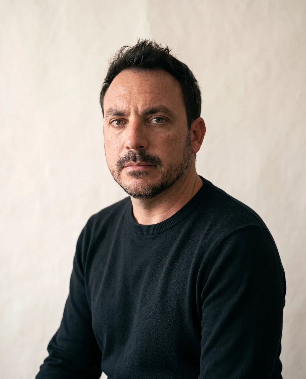 Retrato de Roberto Mickel, de frente, con jersey oscuro sobre fondo de papel claro
